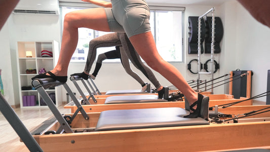 Alumnos realizan un ejercicio de resistencia en Pilates Reformer supervisados por una licenciada en fisioterapia en Panamá.